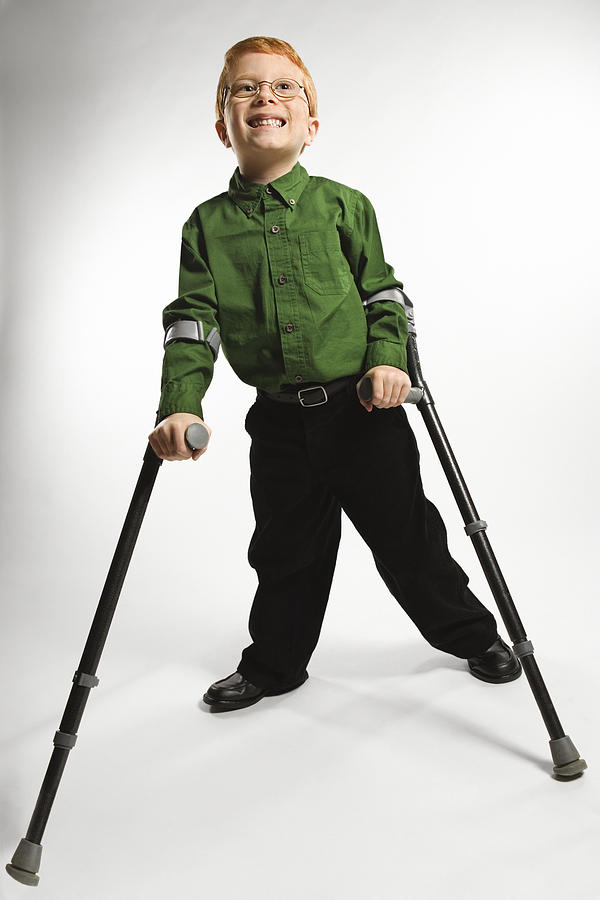 Boy standing with forearm crutches Photograph by Jupiterimages
