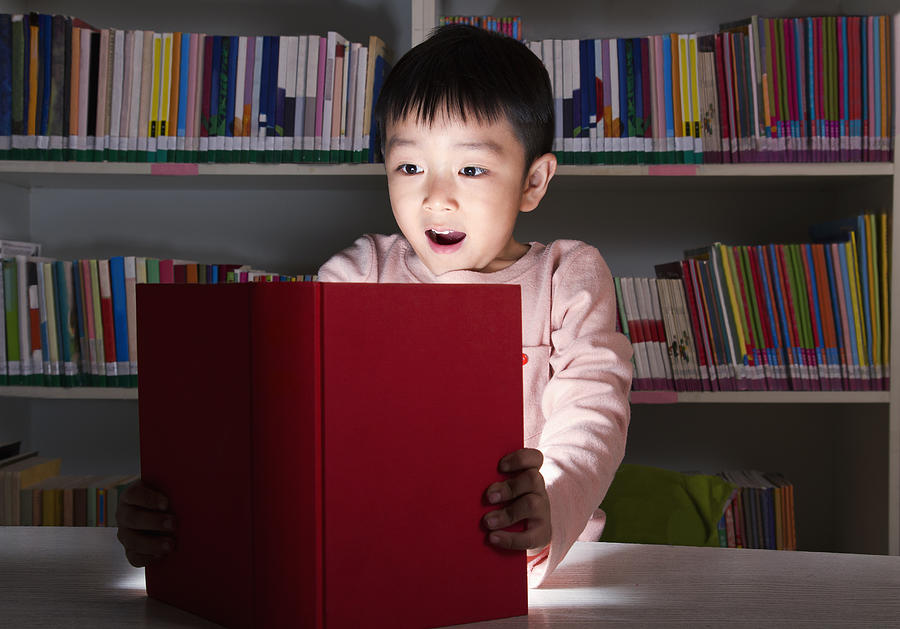 Boy Surprised By Glowing Book Photograph by XiXinXing