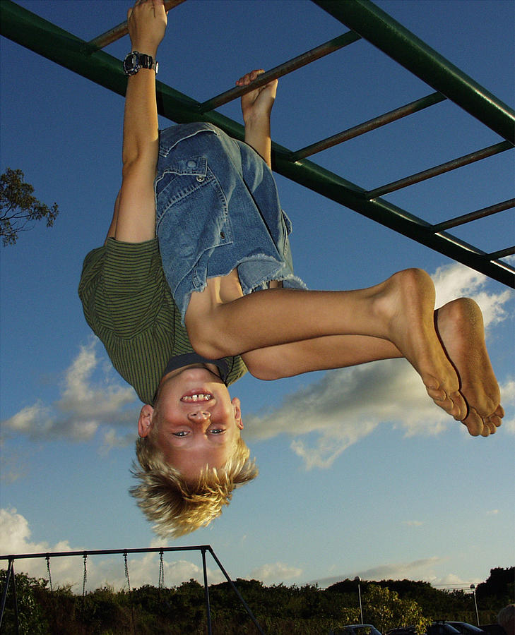Boy upside down on monkey bars Photograph by Thinkstock