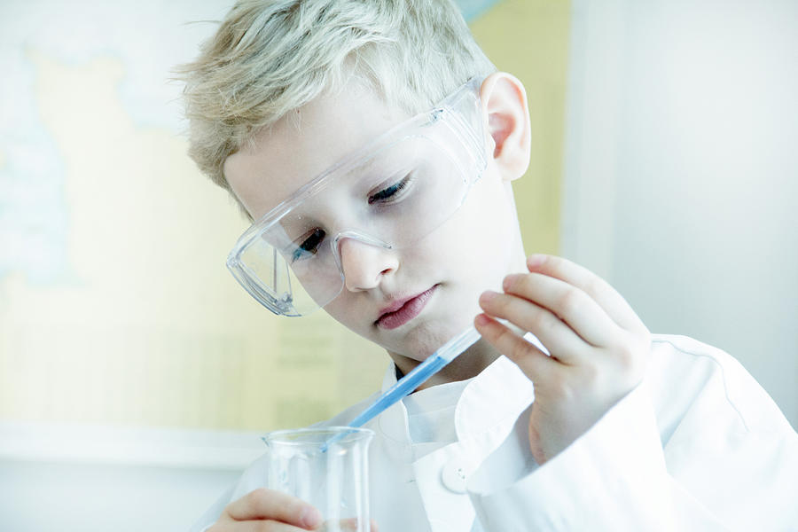 Boy wearing safety goggles doing science experiment Photograph by Sigrid Gombert