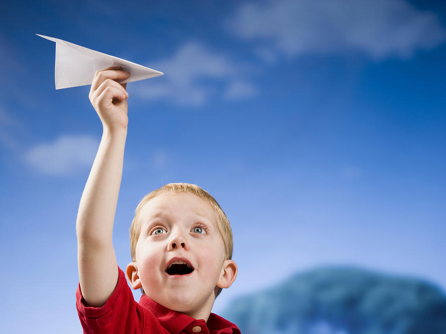 Boy with paper airplane outdoors Photograph by Mike Kemp
