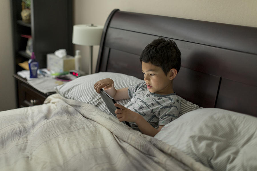 Boy with Tablet Computer in Bed Photograph by JasonDoiy