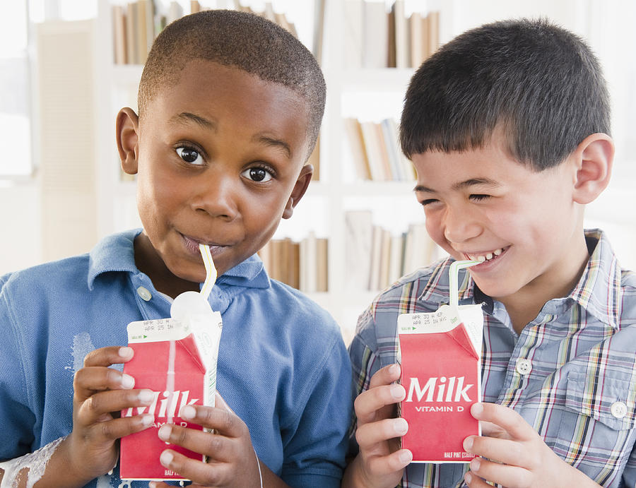 Boys drinking milk from carton Photograph by JGI/Jamie Grill