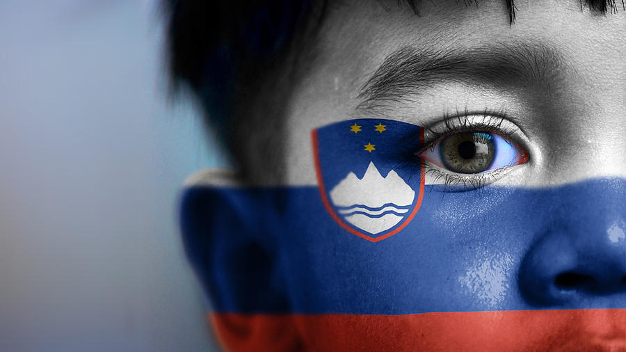 Boys face, looking at camera, cropped view with digitally placed Slovenia flag on his face. Photograph by Mariano Sayno