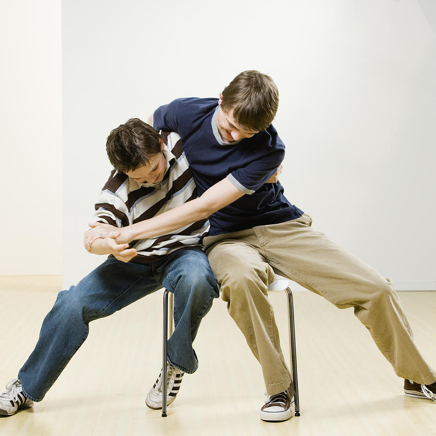 Boys fighting on chair Photograph by Andersen Ross