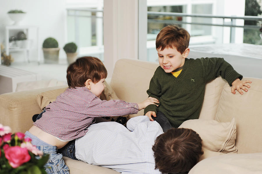 Boys playing on the sofa Photograph by G&J Fey