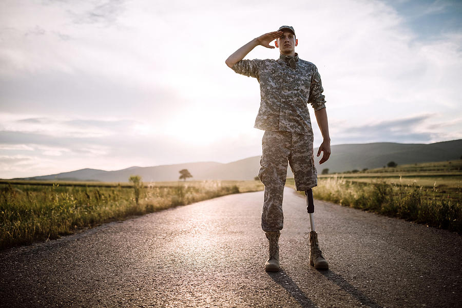 Brave soldier with prosthetic leg saluting on road Photograph by Pekic
