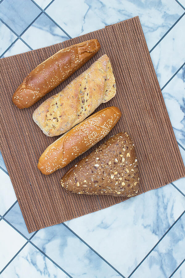 Bread with sunflower seeds and sesame seeds on  wicker napkin Photograph by Olenaa
