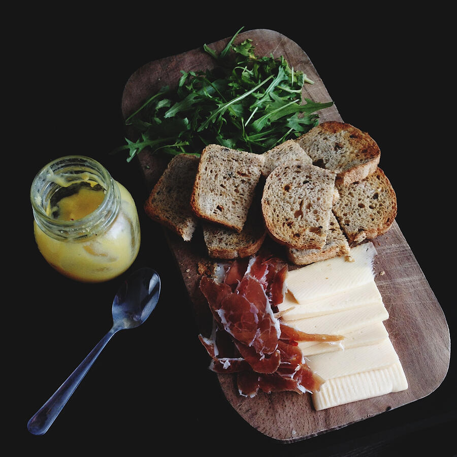 Breakfast board with bread, cheese, rocket leaves, prosciutto and a yogurt Photograph by Foxline