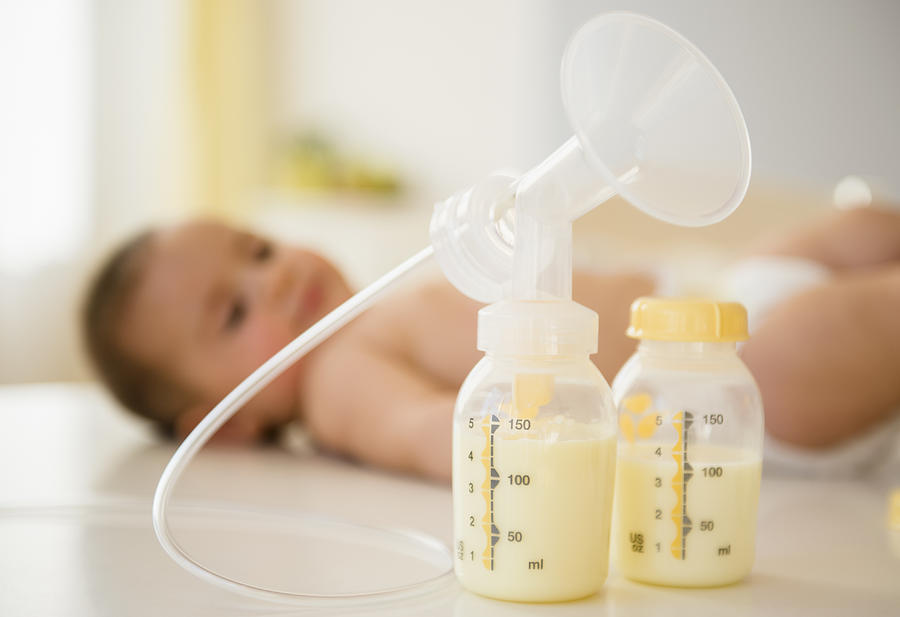 Breast pump next to baby Photograph by Jamie Grill
