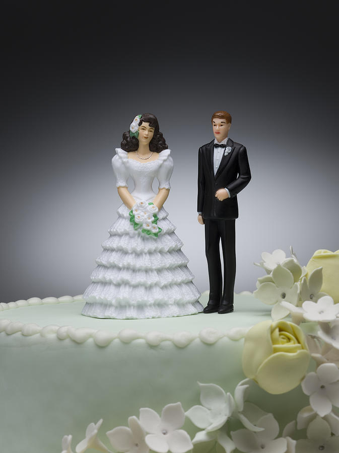 Bride and groom figurines on top of wedding cake Photograph by Jeffrey Hamilton