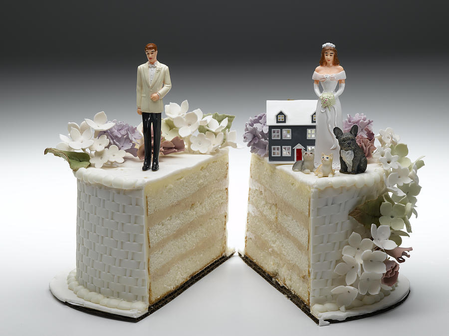 Bride and groom figurines standing on two separated slices of wedding cake Photograph by Jeffrey Hamilton