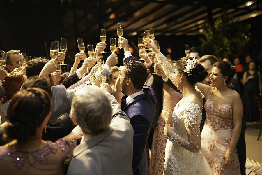 Bride, groom and wedding guests making a toast Photograph by FG Trade