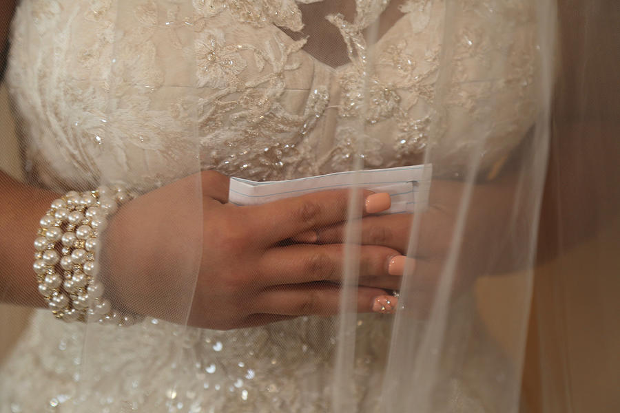 Bride holding written vows, hands clasped Photograph by Holly Harris