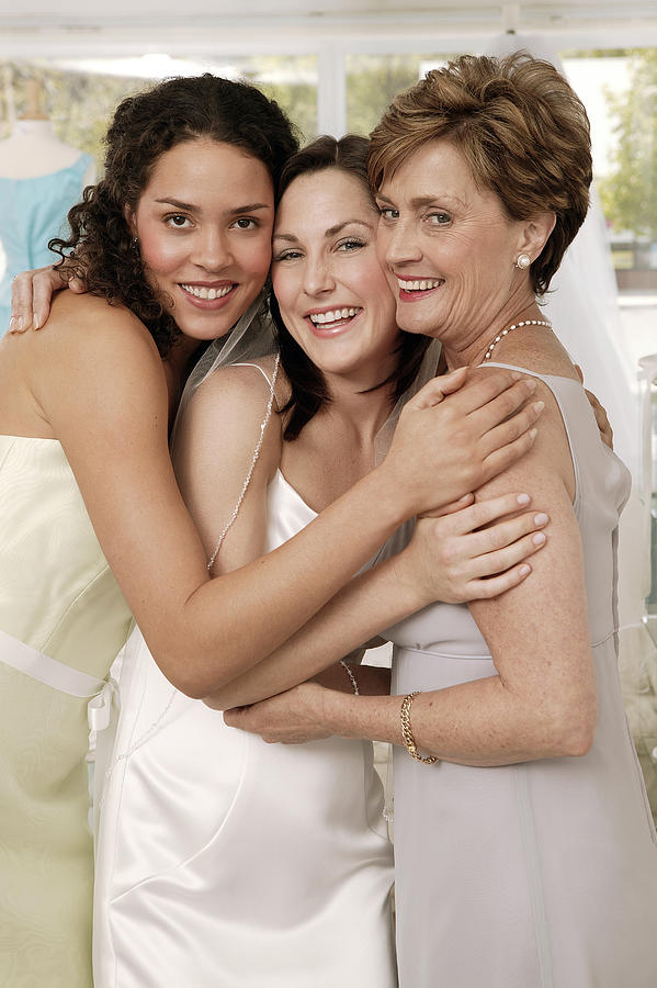 Bridesmaid and mother hugging bride Photograph by Comstock Images