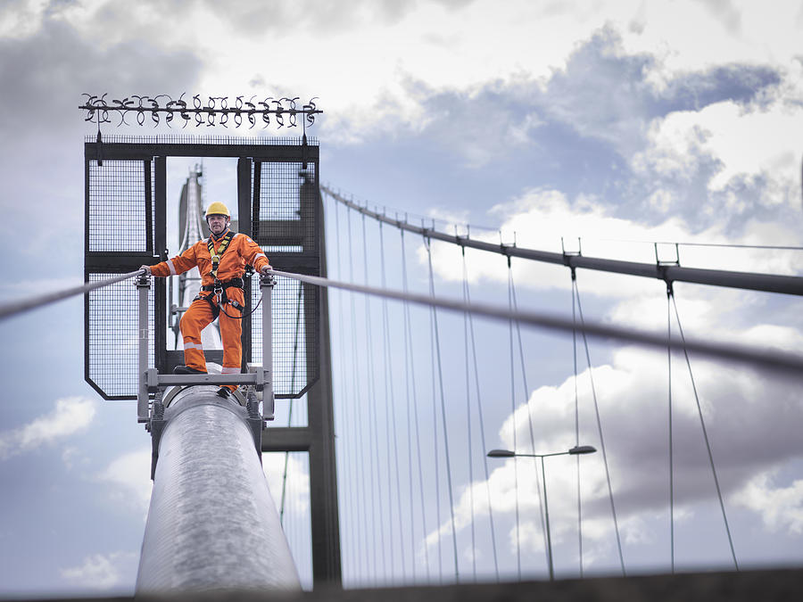 Bridge worker on cable of suspension bridge. The Humber Bridge, UK was built in 1981 and at the time was the worlds largest single-span suspension bridge Photograph by Monty Rakusen