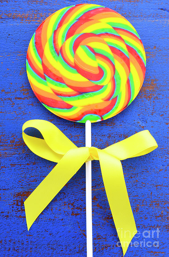 Candy Photograph - Bright rainbow lollipop candy on dark blue wood table.  by Milleflore Images