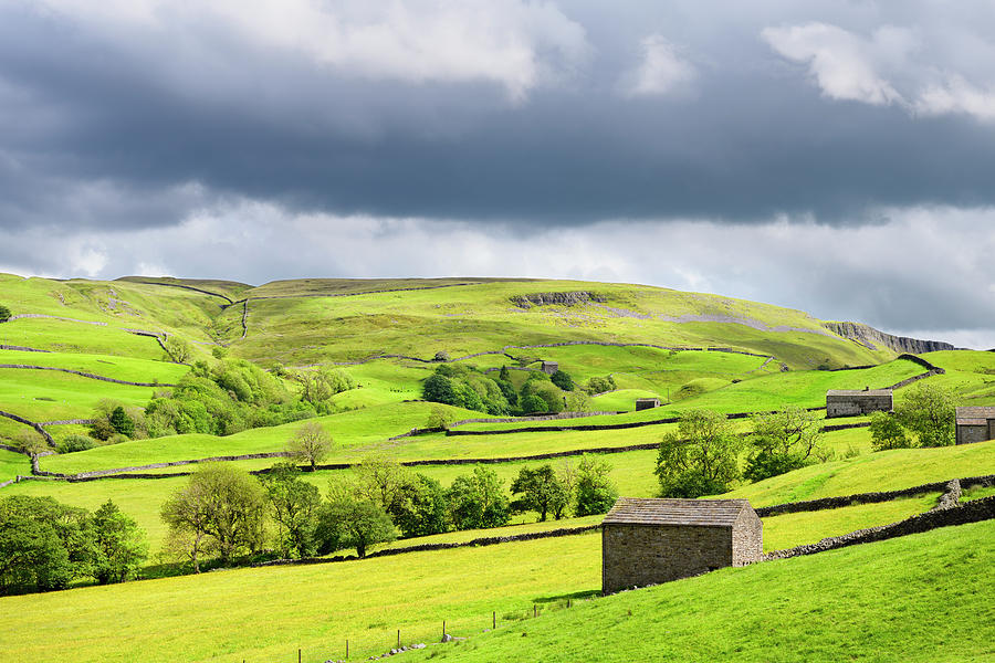 Bright sun with dark clouds over Swaledale drystone walls and ba Photograph by Reimar Gaertner
