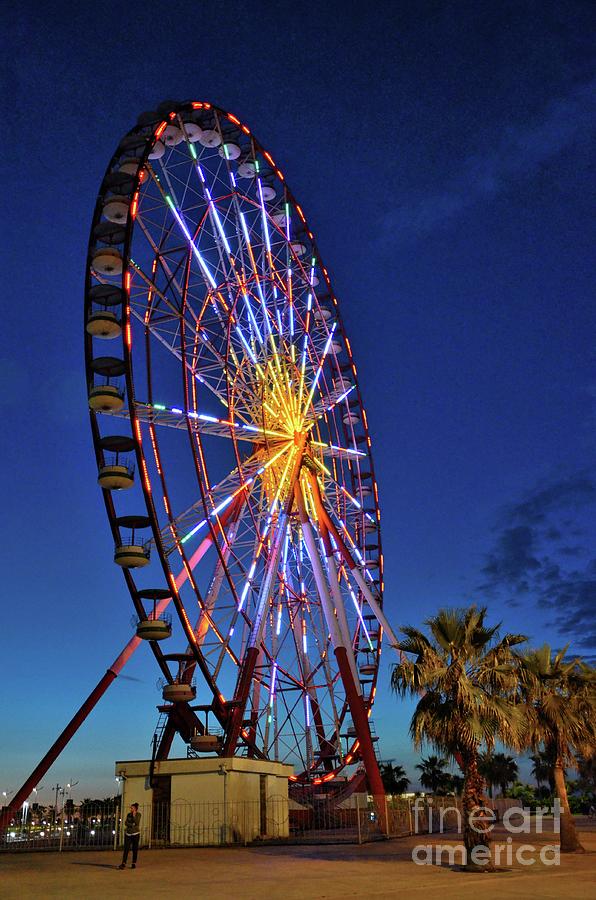 Brightly lit colorful ferris wheel at night in amusement park area Batumi Georgia Photograph by Imran Ahmed