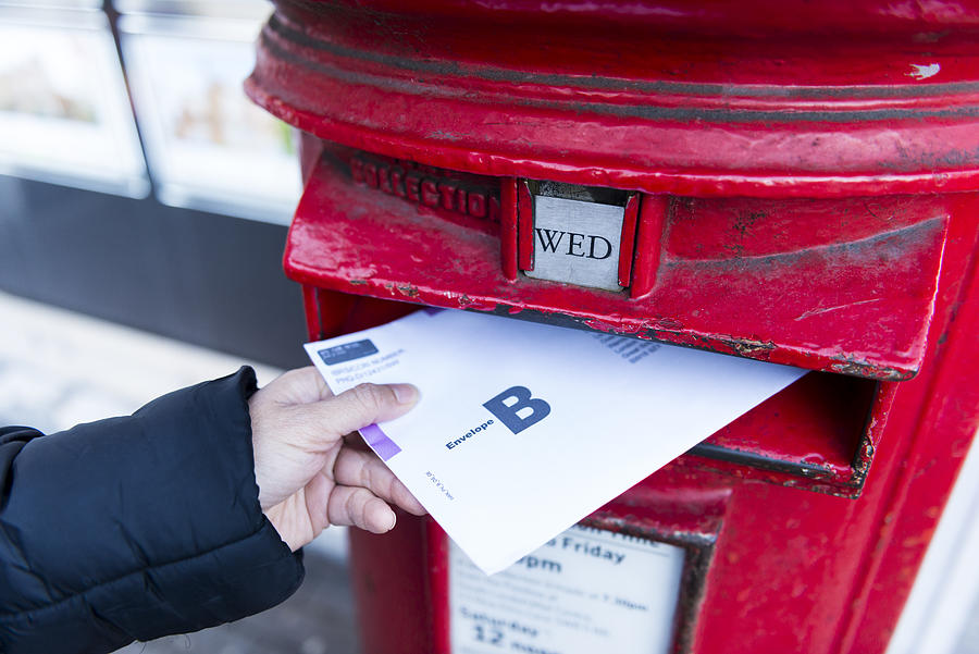 British Postal voting envelop is being dropping into a postbox Photograph by Sunphol Sorakul
