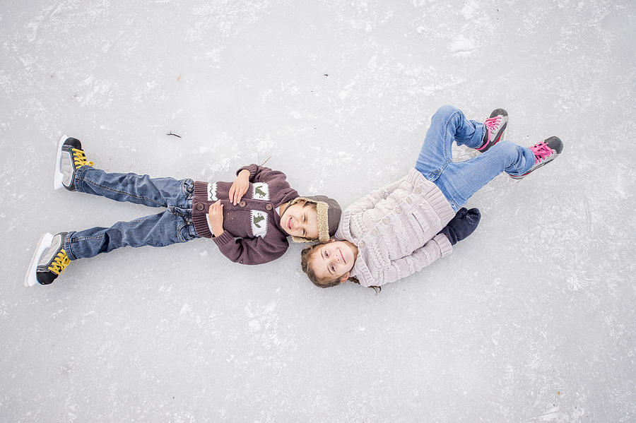 Brother and Sister Lying on a Frozen Pond Photograph by FatCamera