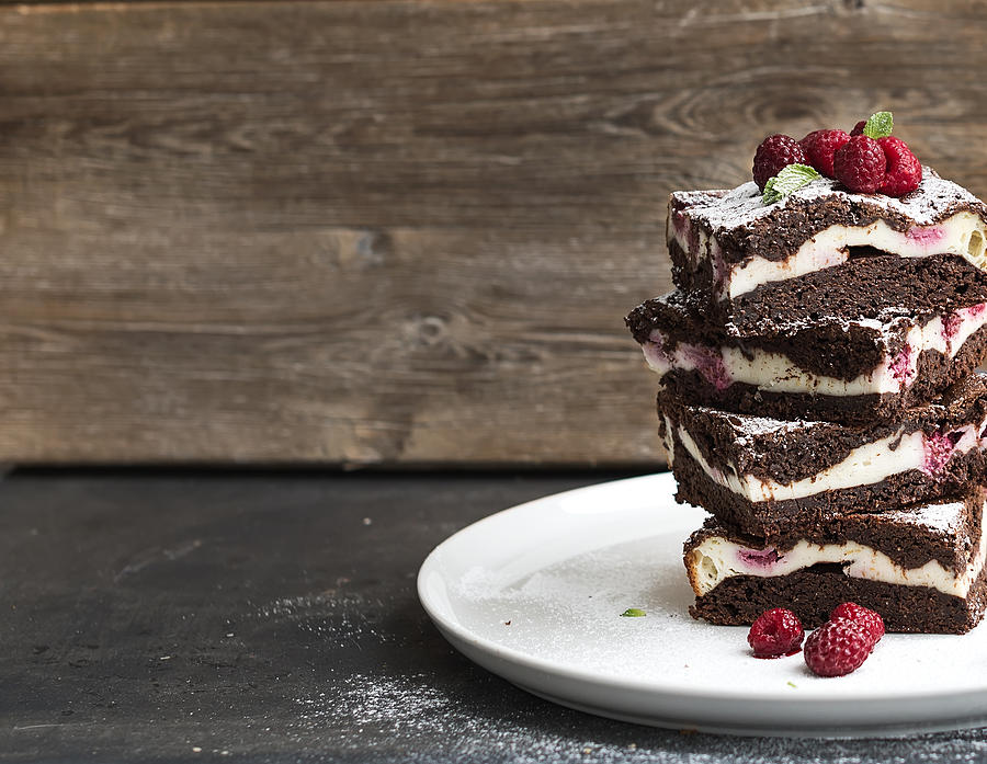Brownies-cheesecake tower with raspberries on white plate, wooden backdrop Photograph by Foxys_forest_manufacture