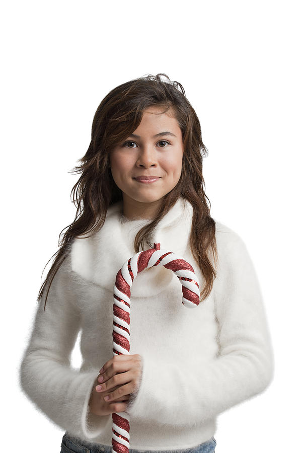 Brunette girl in white holding a candy cane Photograph by Compassionate Eye Foundation/Ryan McVay