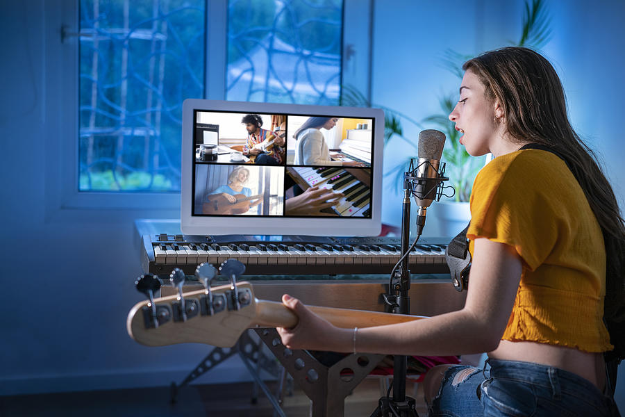 Brunette teen musician singer girl singing and playing bass guitar teleconference Photograph by Mediterranean