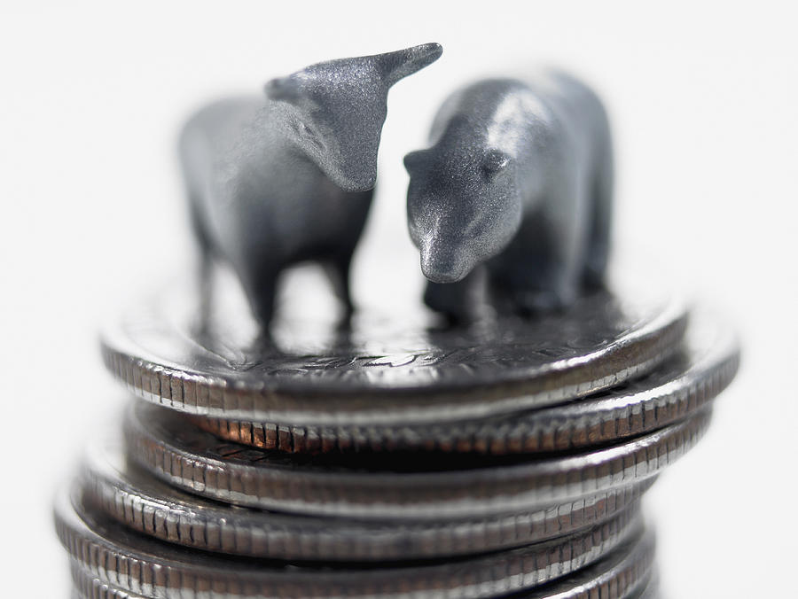 Bull and bear figurines on top of stack of quarters Photograph by Adam Gault
