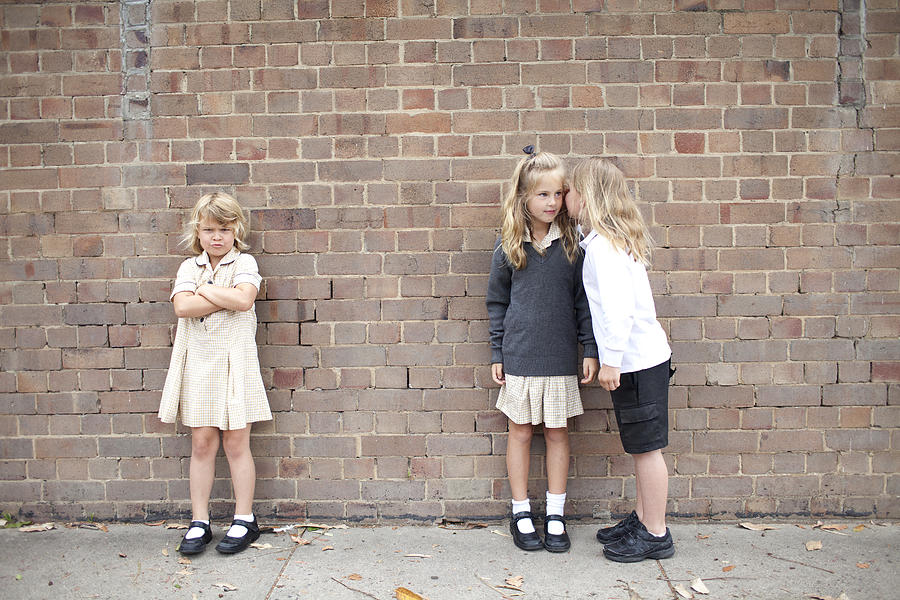 Bullying and whispering in school playground Photograph by Wander Women Collective