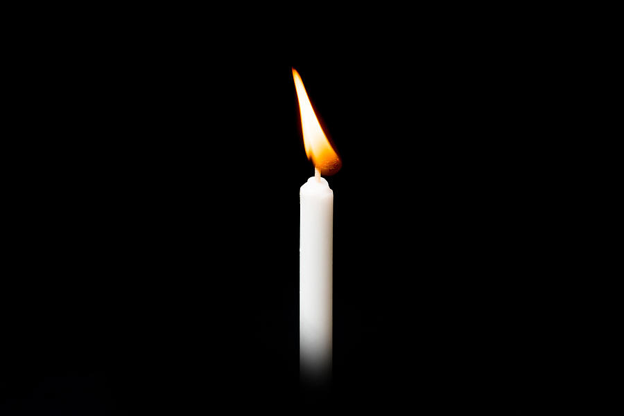 Burning white candle on black background Photograph by Villagemoon