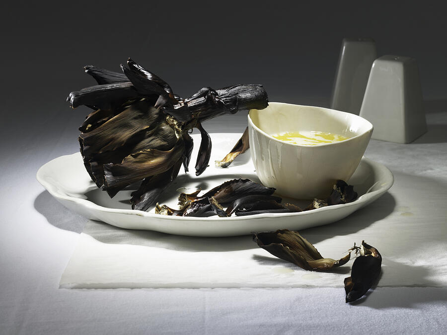 Burnt artichoke with butter on a white plate Photograph by Maren Caruso