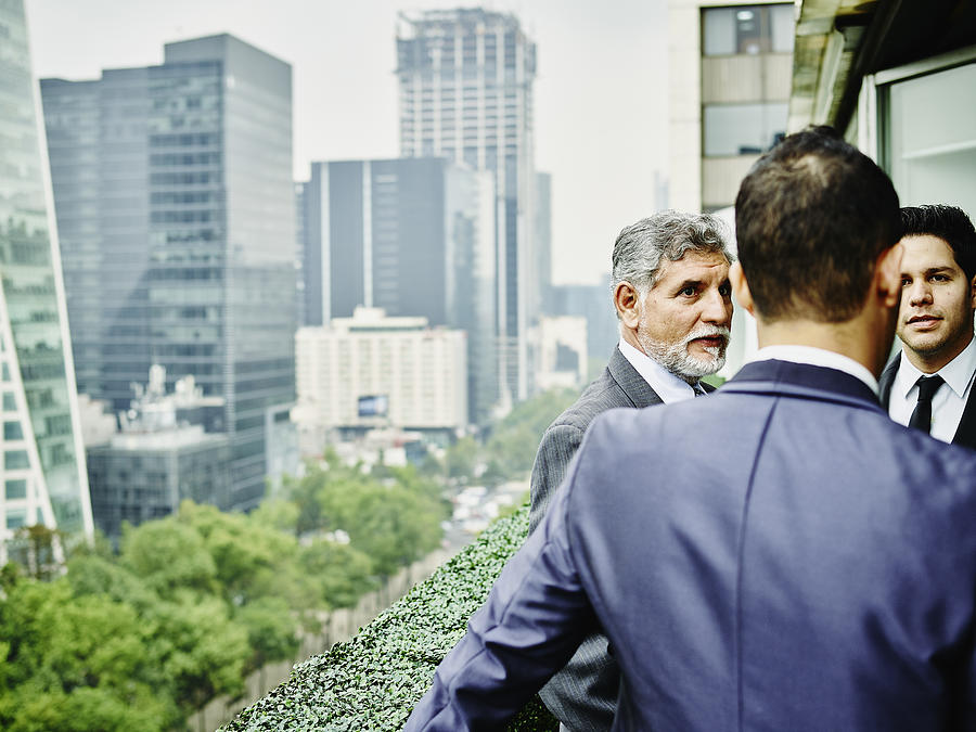 Business executives on terrace overlooking city Photograph by Thomas Barwick