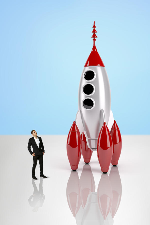 Business man looking at a giant toy rocket ship Photograph by Paper Boat Creative