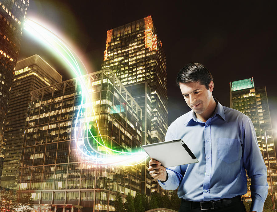 Business man using tablet with city scape behind Photograph by Robert Decelis