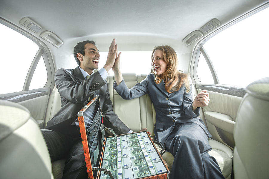 Business people high fiving in backseat of car Photograph by Jon Feingersh Photography Inc