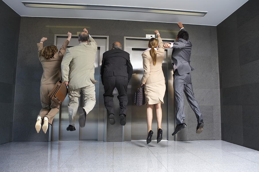 Business People Jumping in Front of Elevator Photograph by Fuse