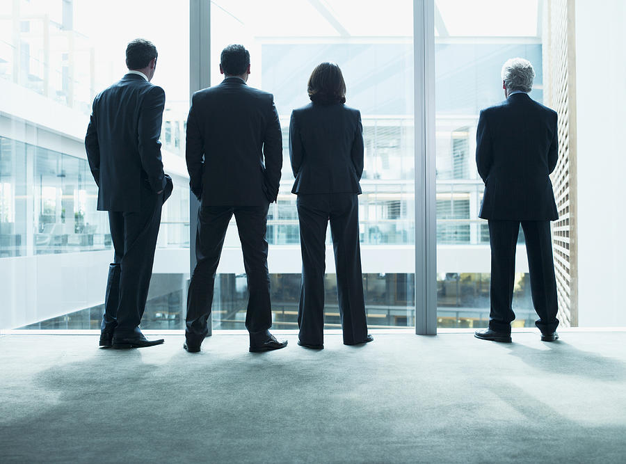 Business people looking out glass wall together Photograph by Martin Barraud