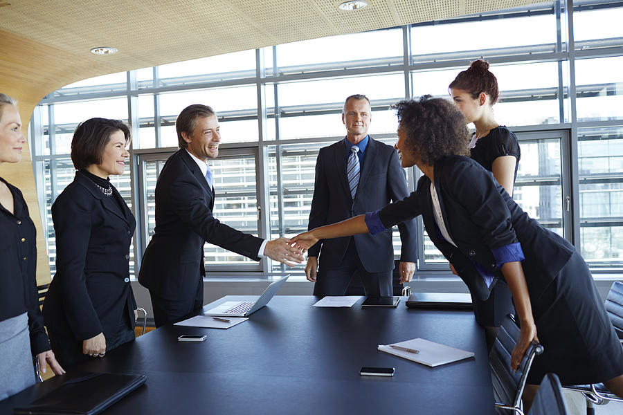 Business people shaking hands across table Photograph by Klaus Vedfelt