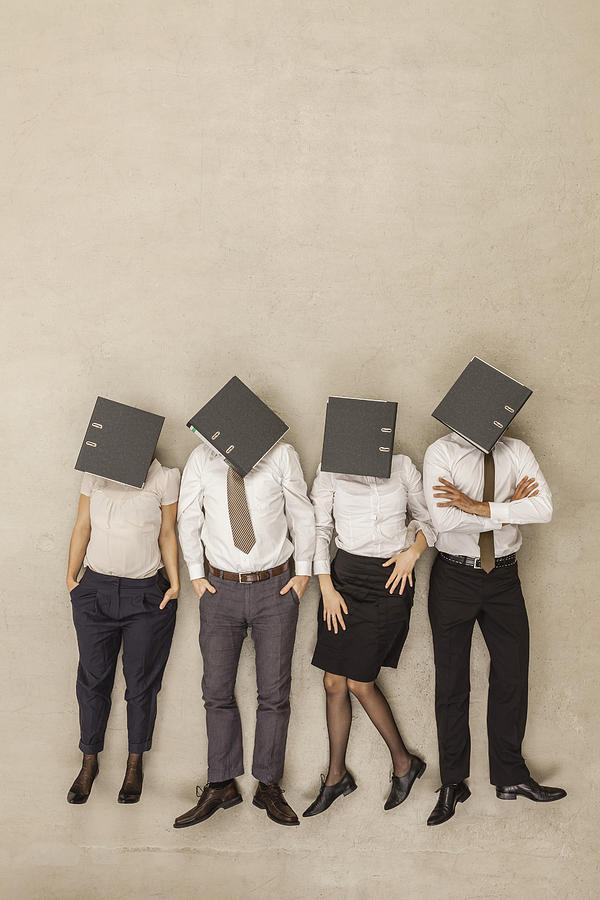 Business people with covered head by folders Photograph by Westend61