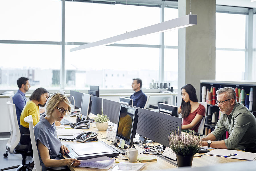 Business people working at desk by windows Photograph by Morsa Images