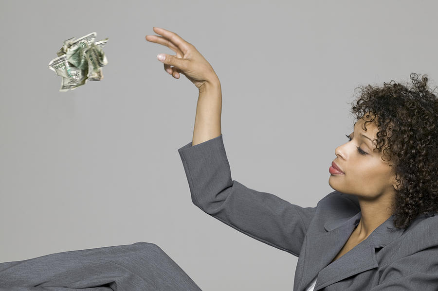 Business Portrait Of A Young Adult Woman In A Grey Suit As She Throws Away Some Cash Photograph by Photodisc