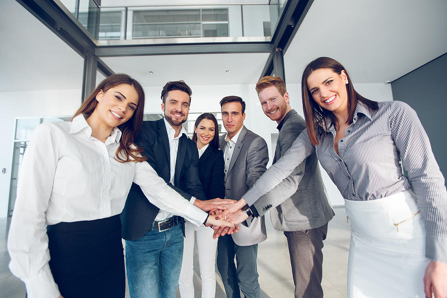 Business team joining hands in a huddle Photograph by EmirMemedovski