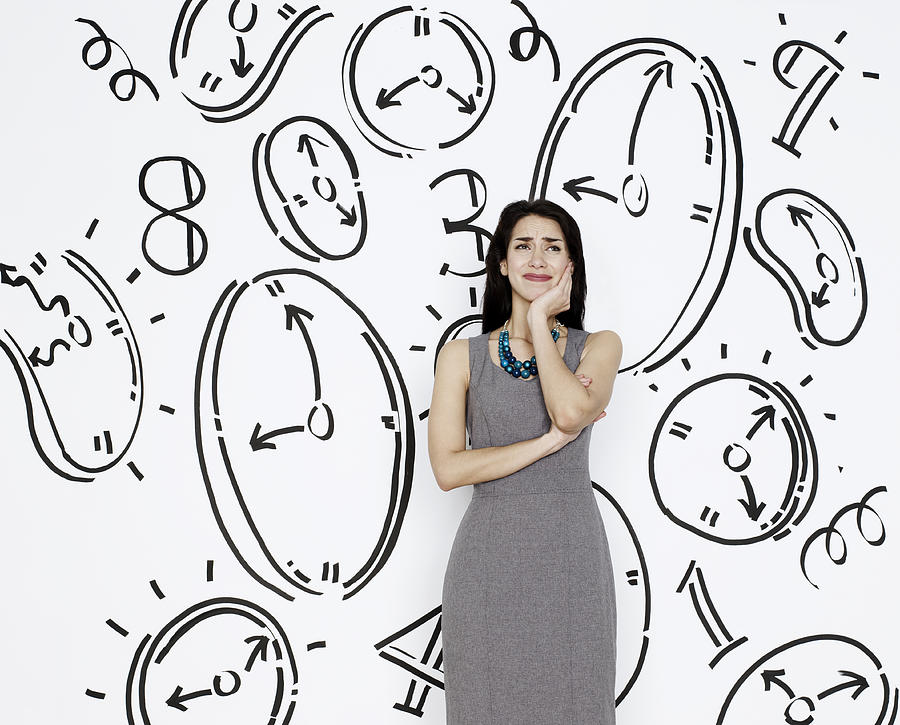 Business woman surrounded by clocks Photograph by Flashpop