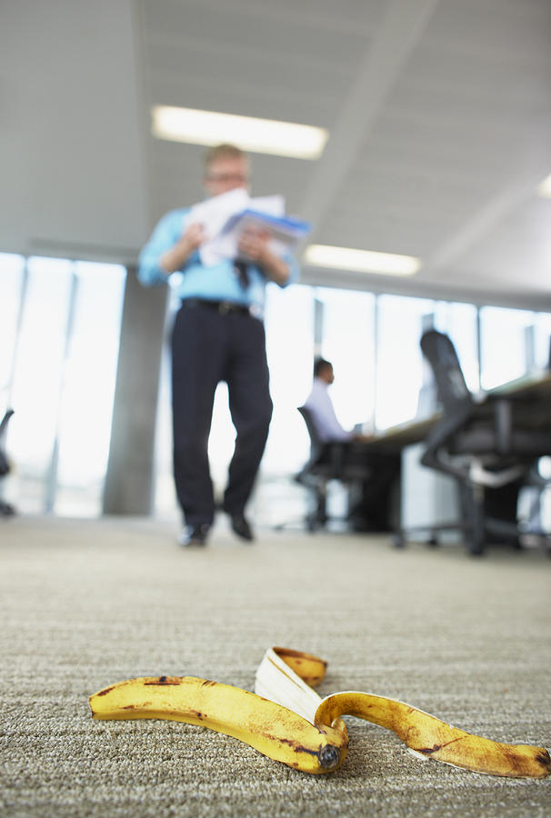 Businessman about to step on banana peel Photograph by Paul Bradbury