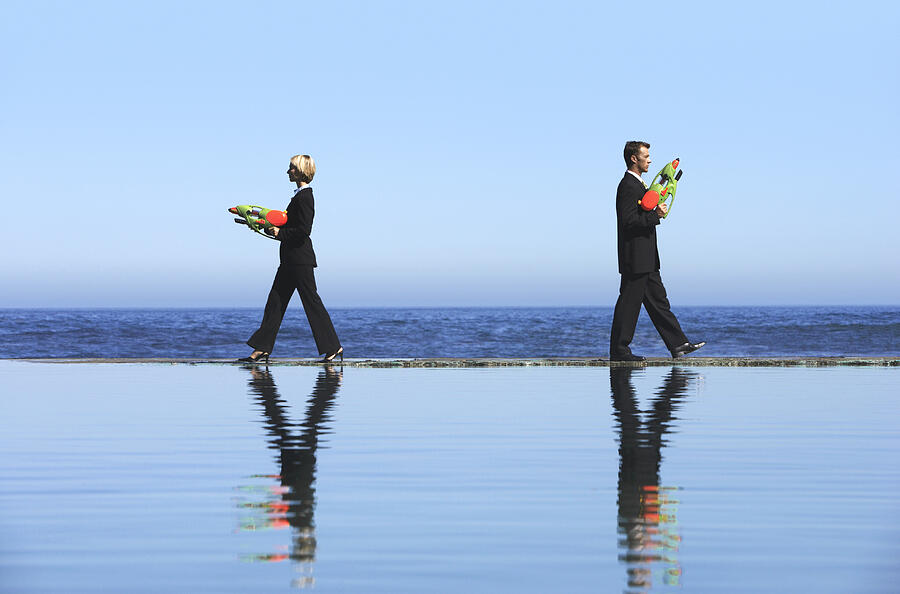 Businessman and a Businesswoman Dueling With Water Pistols by the Sea Photograph by John Cumming