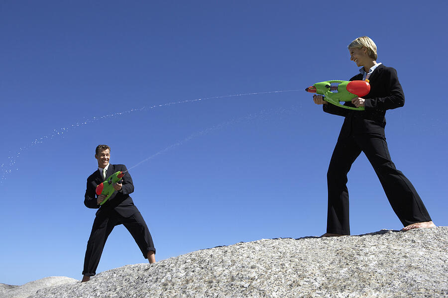 Businessman and a Businesswoman Dueling With Water Pistols Photograph by John Cumming