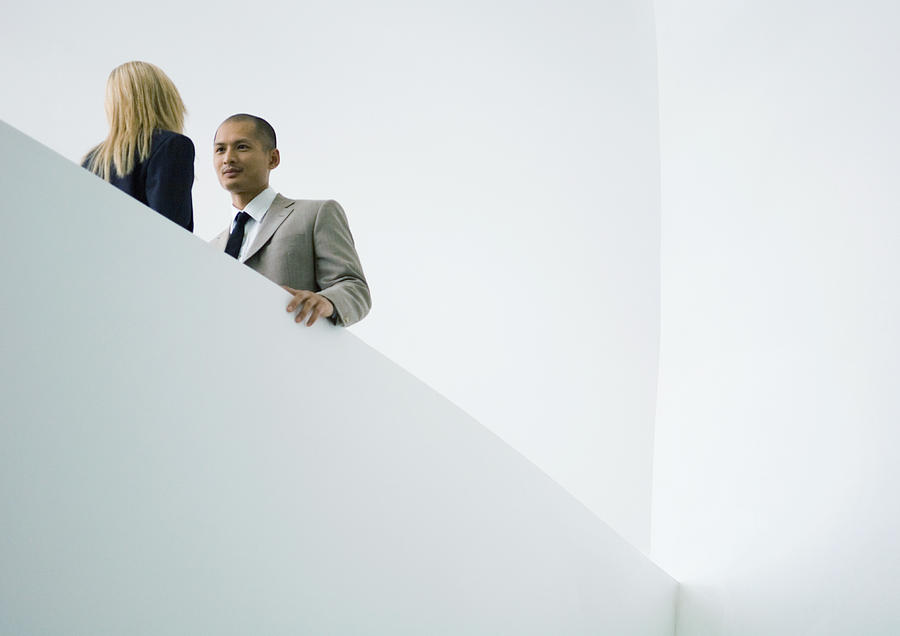 Businessman and businesswoman standing face to face, low angle view Photograph by Eric Audras