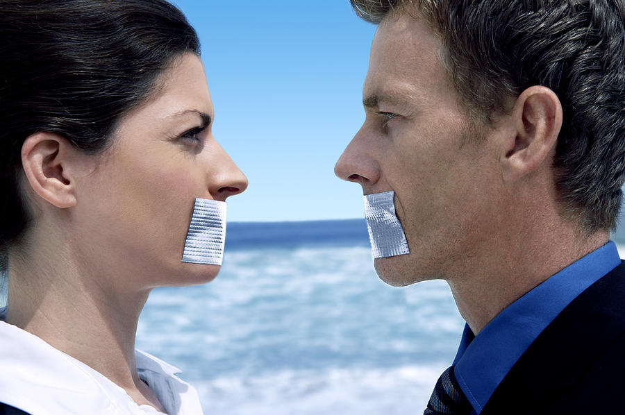 Businessman and Businesswoman Standing Face to Face on a Beach With Their Mouths Covered in Duct Tape Photograph by John Cumming