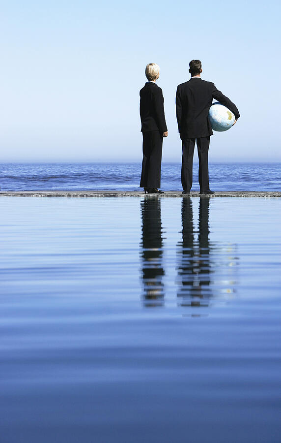 Businessman and Businesswoman Standing Side by Side Looking at the Sea Photograph by John Cumming